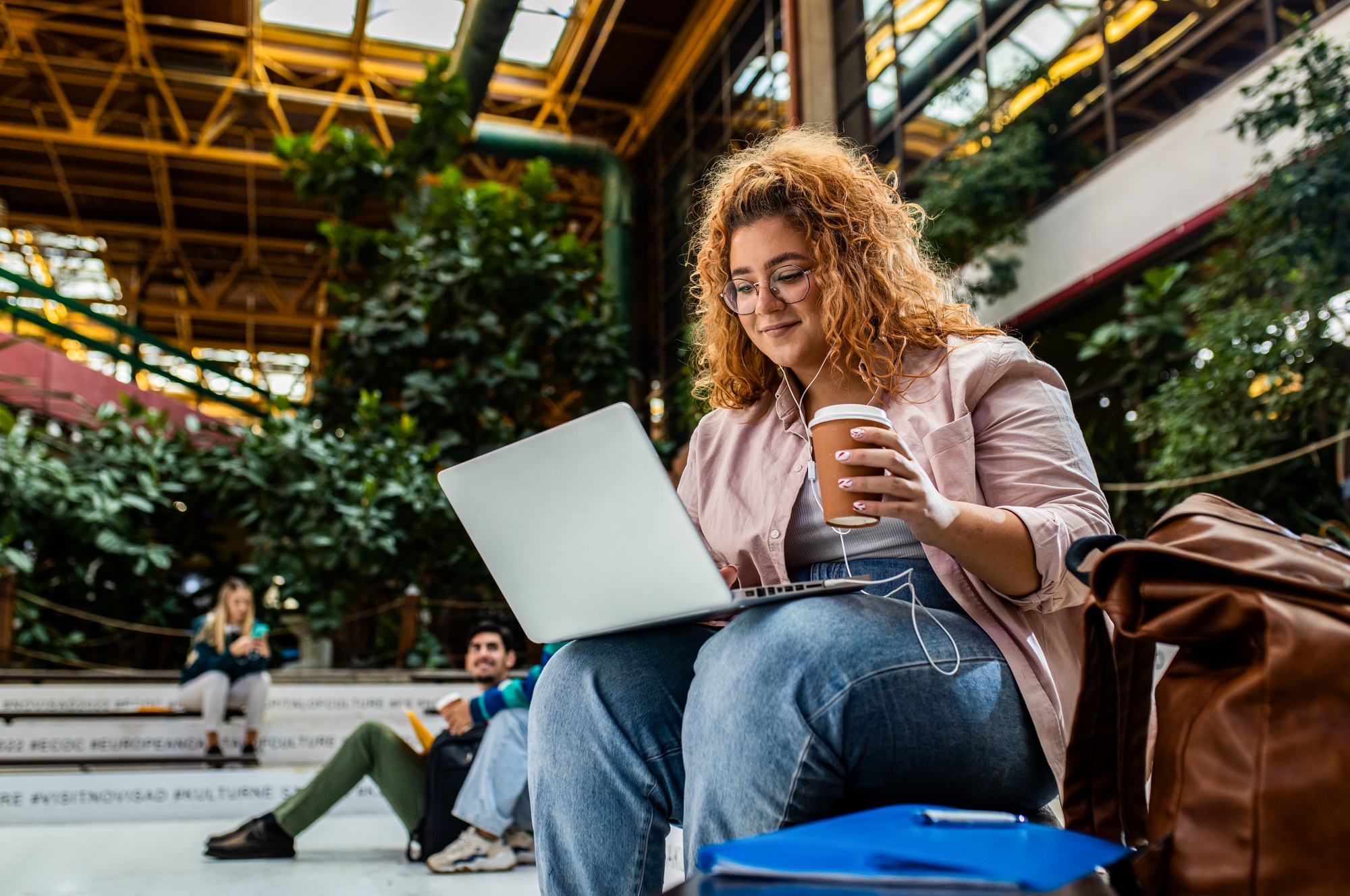 Portrait of female student siting in campus using laptop.